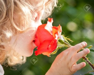 Barn lukter på blomst. Bilde